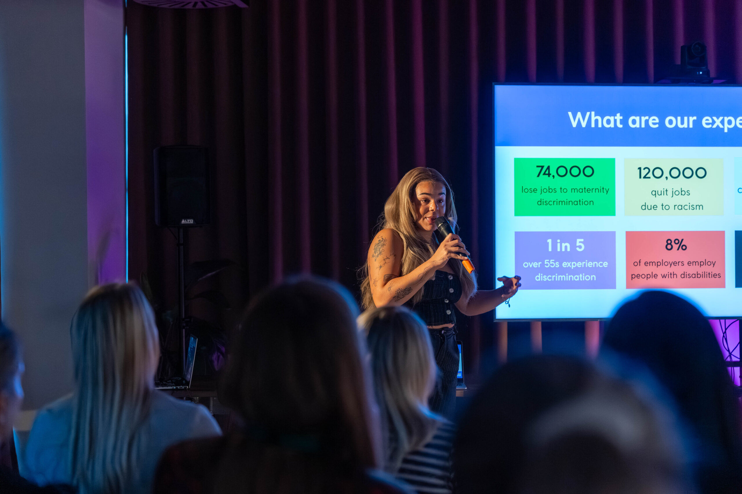 Two women sitting at a table talking with colourful pictures behind